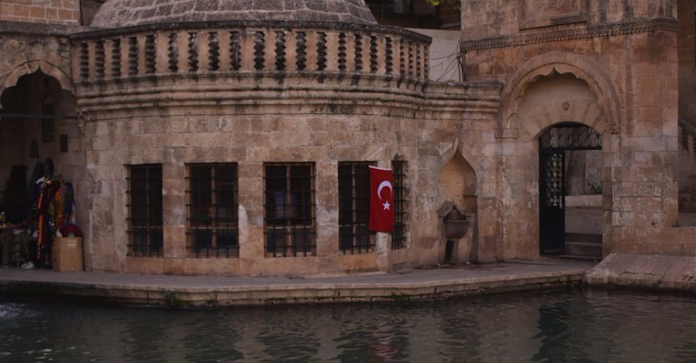 Relaxing Tours - Scenic view of Balikli Gol mosque by the water with Turkish flag.