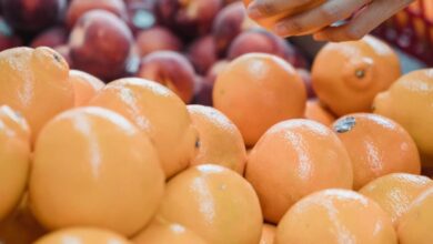 Farmers Market Shopping - Close-up of a hand picking oranges at a vibrant local market.