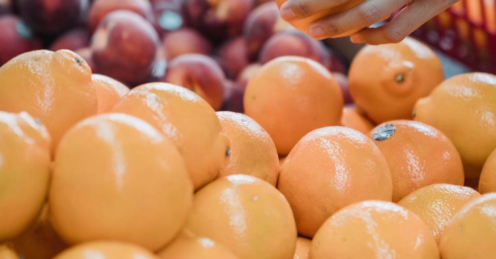 Farmers Market Shopping - Close-up of a hand picking oranges at a vibrant local market.