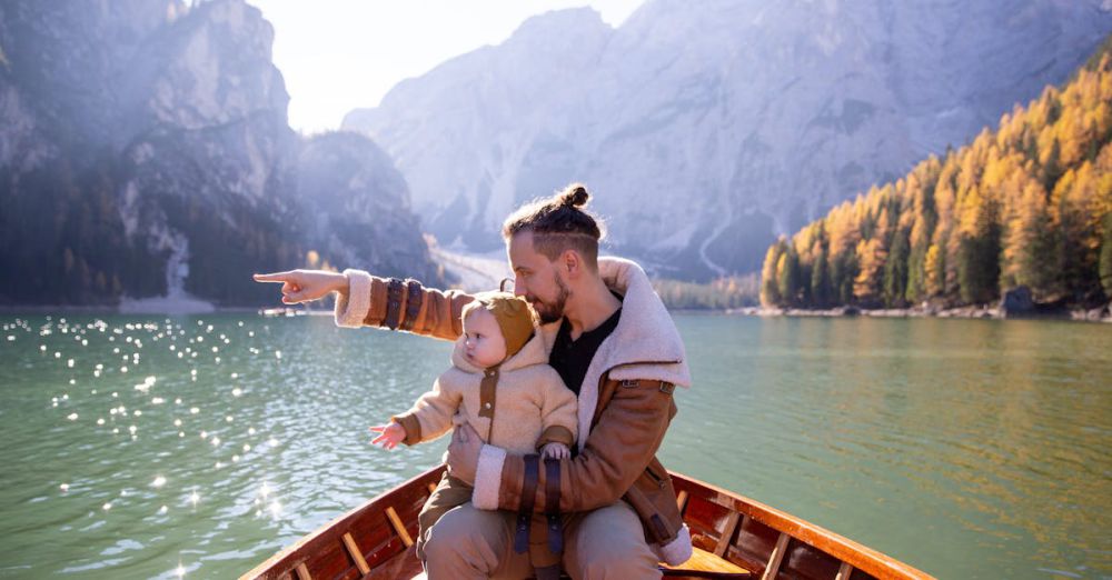 Family Canoe Portaging - A father and baby on a boat pointing at scenic mountain lake view in autumn.