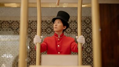 Portaging Navigation - A bellboy in a red uniform stands with a luggage cart inside a luxurious hotel.