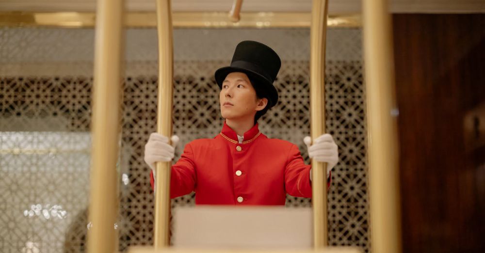 Portaging Navigation - A bellboy in a red uniform stands with a luggage cart inside a luxurious hotel.