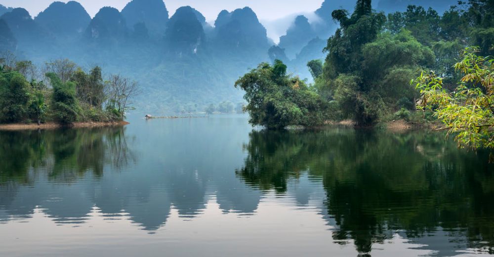 Remote Canoe Portaging - A tranquil river scene with a canoe, misty mountains, and lush greenery, perfect for nature lovers.