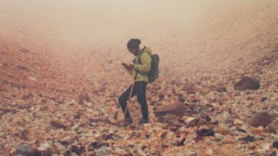 Portaging Trails - A lone hiker navigates a rocky landscape on a misty day.