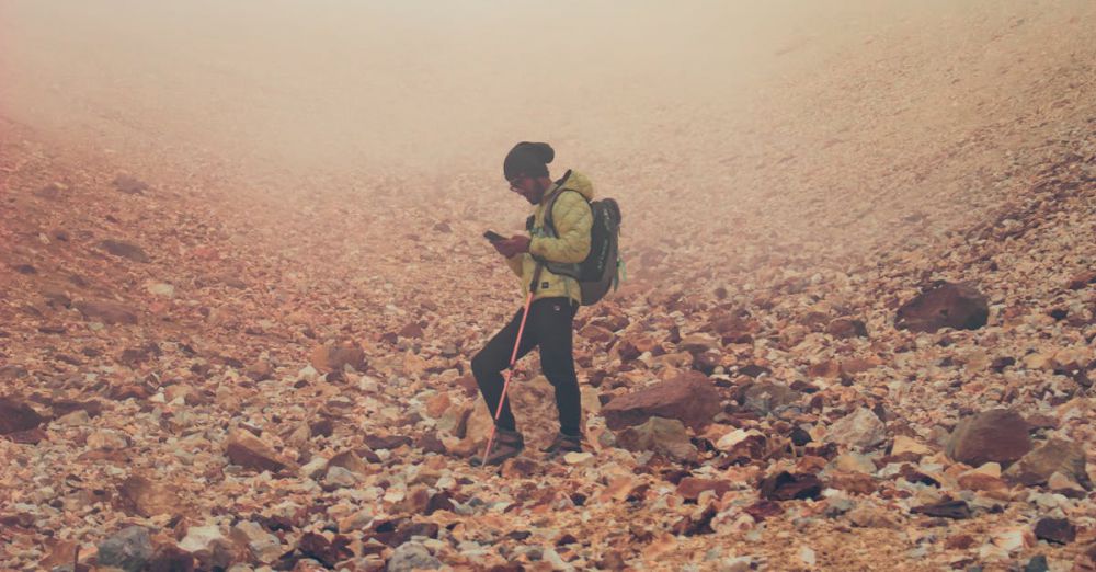 Portaging Trails - A lone hiker navigates a rocky landscape on a misty day.