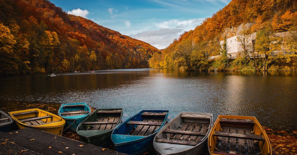 Fall Canoe Portaging - Colorful boats by a lake with vibrant autumn foliage, reflecting tranquility in nature.
