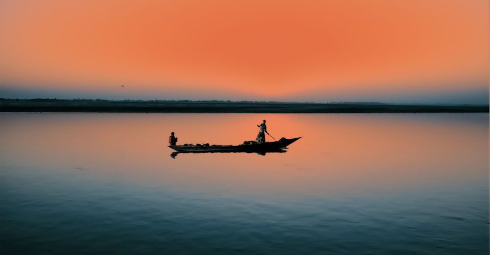 Fishing Canoe Portaging - Silhouette of a canoe at sunrise casting reflection on a placid lake.