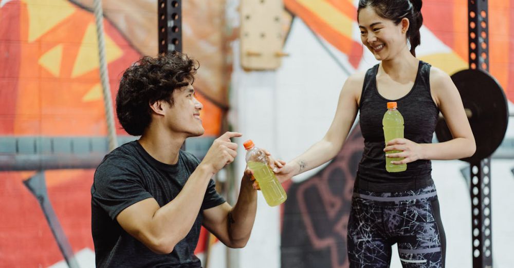 Fitness Gifts - A man and woman sharing sports drinks in an energetic gym setting.