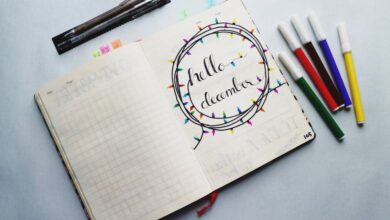 Winter Festival Planning - Open planner with 'Hello December' design surrounded by colorful markers, perfect for planning inspiration.