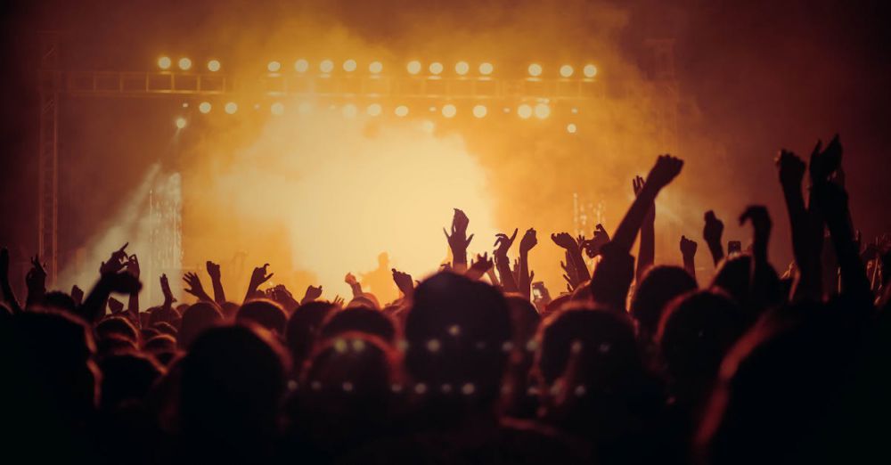 Live Music Festivals - Energetic music concert with a vibrant crowd cheering under bright stage lights.