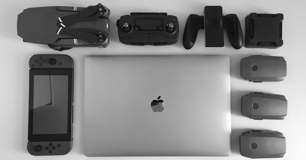 Gadgets - A black and white flat lay of various modern tech gadgets including a laptop, drone, and gaming device.