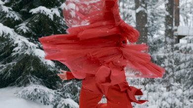Ice Skating Festivals - Dynamic image of a figure skater in red twirling on ice amidst a snowy forest. Captivating winter scene.
