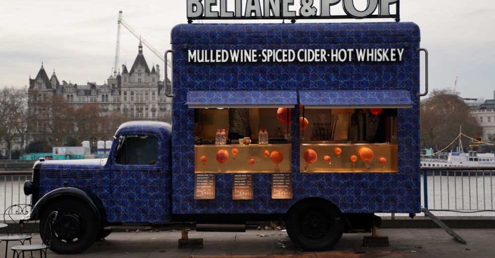 Food Truck Winter Festivals - Colorful food truck serving mulled wine, spiced cider, and hot whiskey by the riverside with cityscape backdrop.