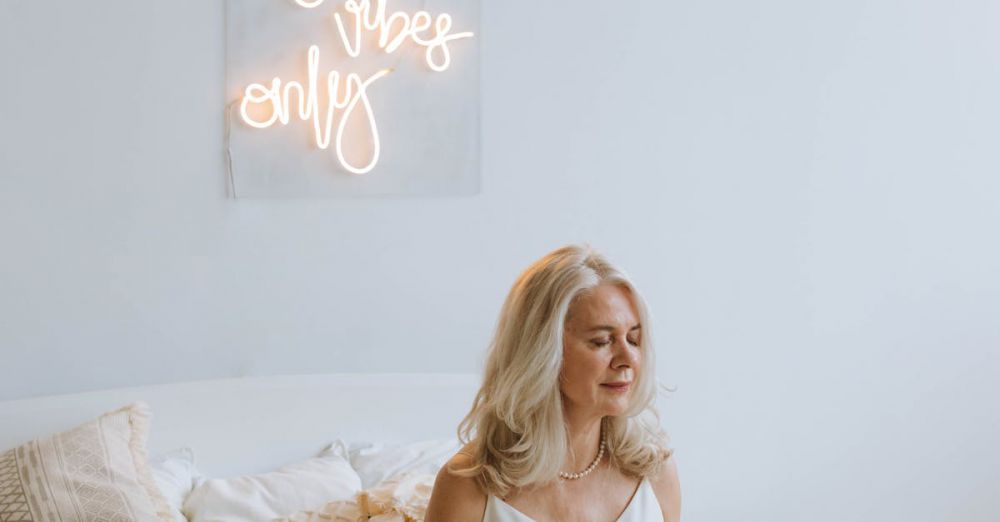 Wellness Gifts - Serene woman meditating on a cozy bed under 'Good Vibes Only' neon sign.