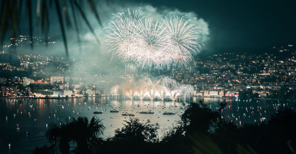 Ski & Snowboard Festivals - Nighttime fireworks display over Lugano, Switzerland, lighting up the lake and cityscape.