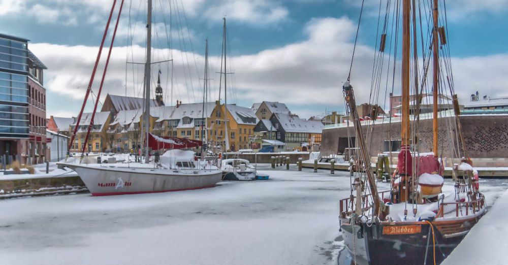 Ice Fishing Festivals - Snow-covered boats docked in a serene winter harbor in Stralsund, Germany.