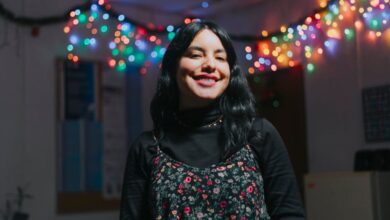 Winter Festival Finder - Young woman smiling indoors with colorful festive lights.