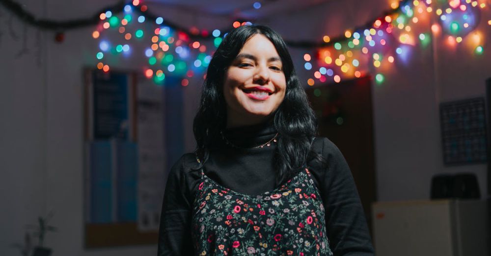 Winter Festival Finder - Young woman smiling indoors with colorful festive lights.