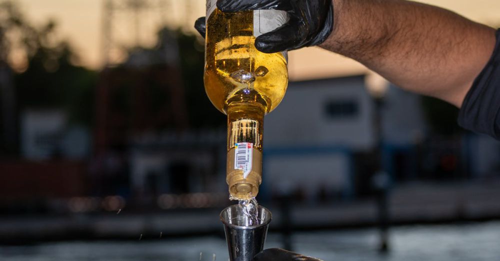 Craft Beer & Cider Festivals - Gloved bartender pours beer into glass at an outdoor bar against a sunset backdrop.