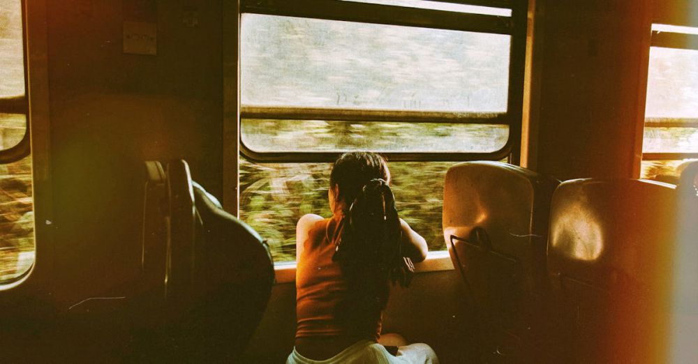 Scenic Train Ride Planning - A woman gazes out of a train window, enjoying a serene journey through lush scenery.