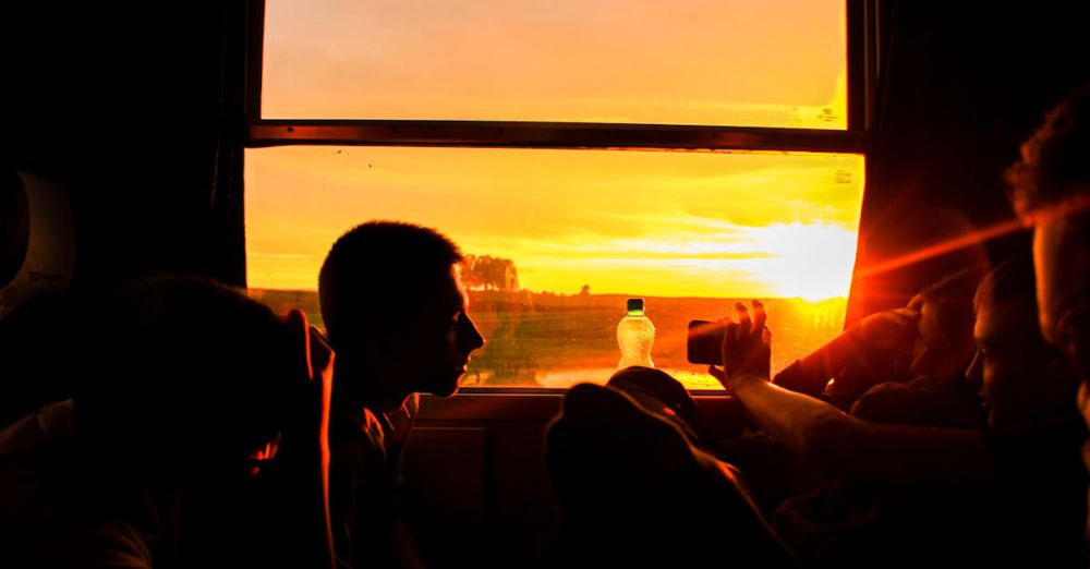 Photography Scenic Train Rides - Silhouette of people on a train capturing a vivid sunset through a window.