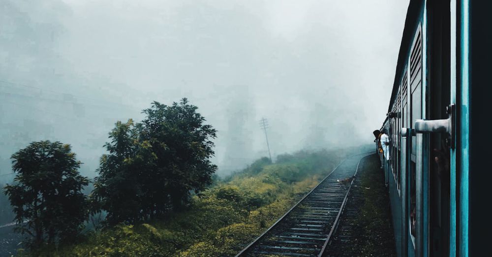 Adventure Scenic Train Rides - A train travels through a foggy countryside with railway tracks disappearing into the mist.