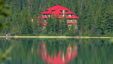 River Scenic Train Rides - Red lodge reflecting in calm lake amid lush forest in Jasper, Alberta.