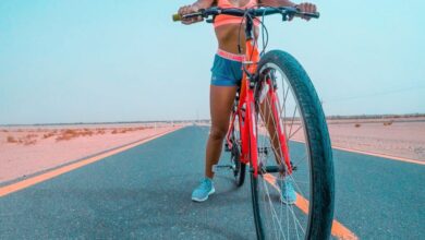 Desert Scenic Train Rides - A woman cyclist in athletic gear on a bike in the Dubai desert, promoting fitness and adventure.