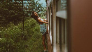 Scenic Train Ride Choice - Woman enjoying a thrilling train ride, leaning out a window amidst lush greenery.