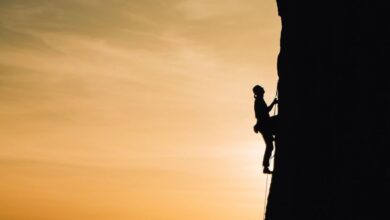 Rock Climbing - A silhouette of a rock climber scaling a steep cliff during sunset in Russia, showcasing determination and adventure.