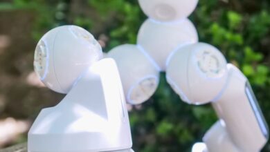 Advanced Rock Climbing - Close-up of a futuristic white robotic arm stepping over a rock outdoors.