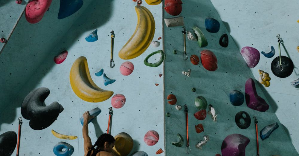 Indoor Rock Climbing - A woman ascends a colorful indoor rock wall in a gym setting, showcasing skill and focus.