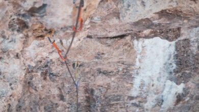 Trad Climbing - From above of stony uneven terrain with water flowing on rocks of cliff and safety rope in wild nature in daytime