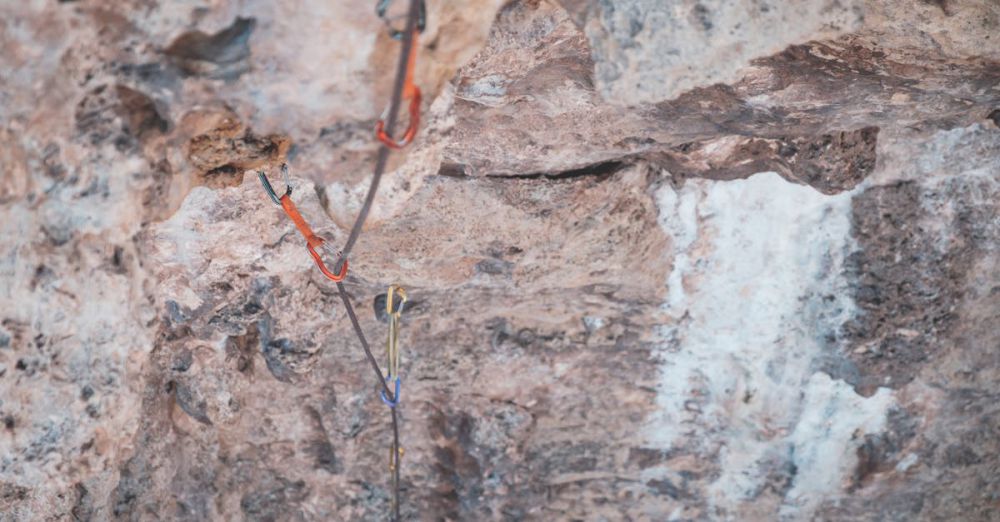 Trad Climbing - From above of stony uneven terrain with water flowing on rocks of cliff and safety rope in wild nature in daytime