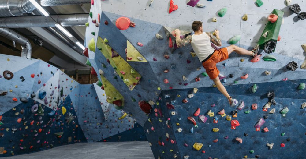 Sport Climbing - Man bouldering on colorful indoor climbing wall, showcasing athletic skills.