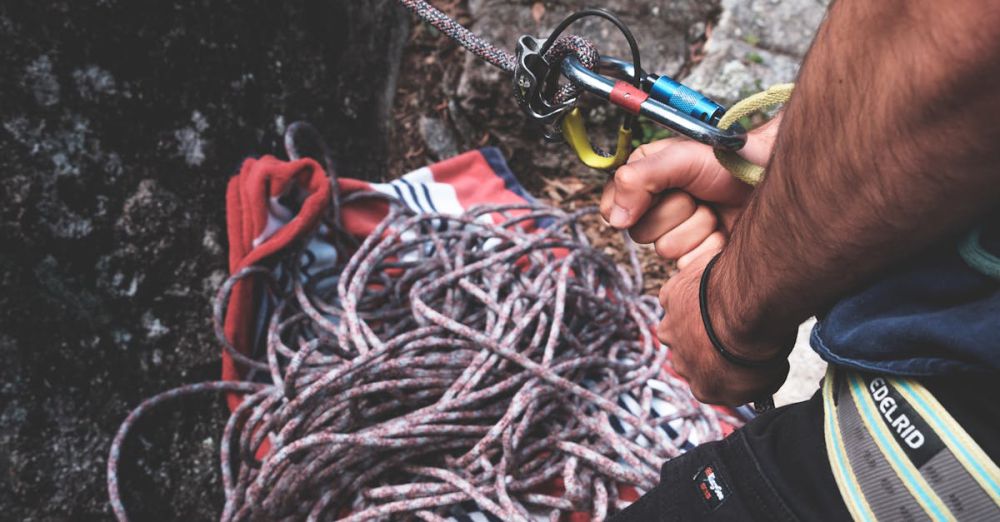 Rock Climbing Preparation - Unrecognizable climber with belay harness with carabines on rope standing near rocky cliff while preparing for mountaineering training in nature