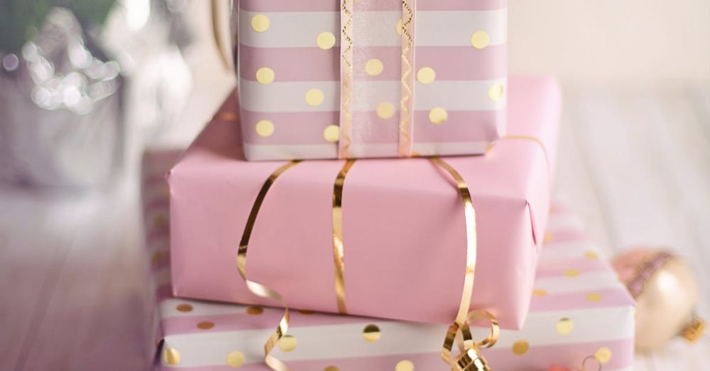 Gifts - Charming Christmas presents wrapped in pink and gold with festive ornaments on a wooden table.