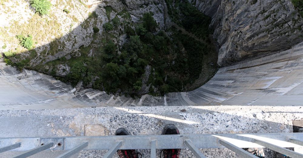 Overhang Rock Climbing - A thrilling view from the edge of a Swiss dam, showcasing the depth below.