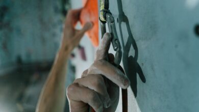 Technical Climbing - Detailed shot of hands using a carabiner while rock climbing indoors, conveying action and focus.