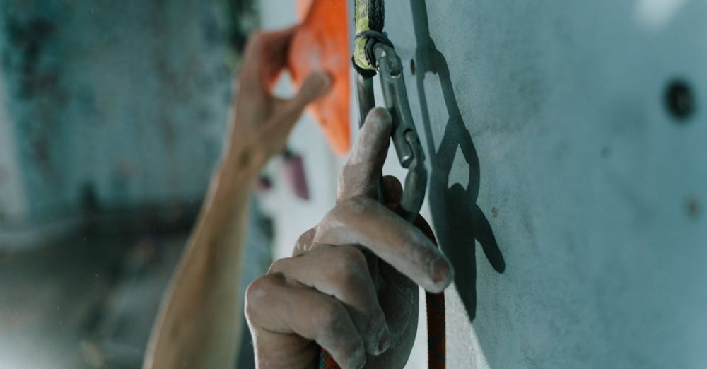 Technical Climbing - Detailed shot of hands using a carabiner while rock climbing indoors, conveying action and focus.