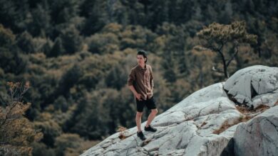 Ontario Rock Climbing - A man standing on white rock surrounded by dense forest in Killarney, Ontario, perfect for nature enthusiasts.