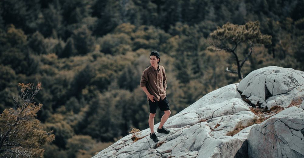 Ontario Rock Climbing - A man standing on white rock surrounded by dense forest in Killarney, Ontario, perfect for nature enthusiasts.