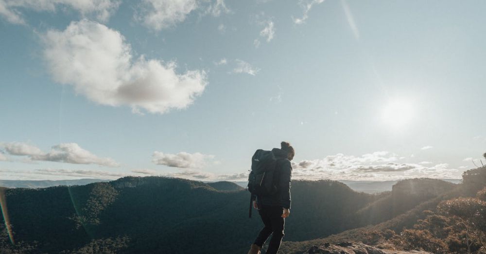 Mixed Rock Climbing - A lone hiker stands on a mountain ridge under a bright morning sky, embracing the tranquility of nature.