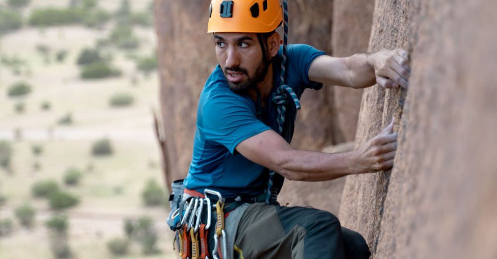 Rock Climbing Route Choice - A focused climber with safety gear ascends a rock face outdoors.