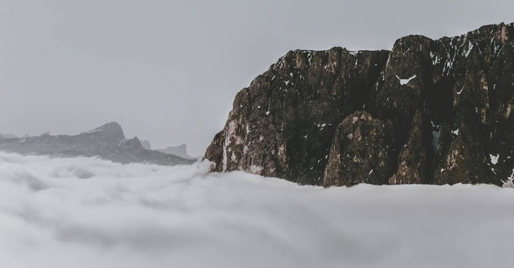 Photography Rock Climbing - Majestic Dolomites mountain peak rising through a sea of clouds, creating a serene and dramatic winter scene.