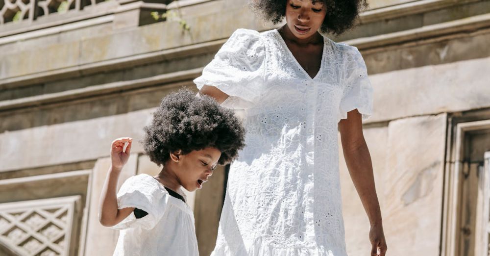 Family Urban Gardens - A heartfelt moment of a mother and daughter in white dresses walking down ornate stone steps outdoors.