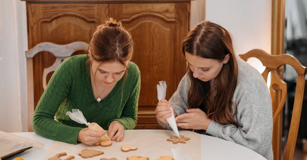 Cooking Gifts - Two young women joyfully decorating cookies at home for Christmas.