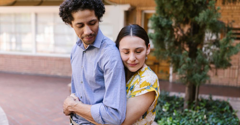 Peaceful Urban Gardens - Young couple hugging affectionately outside near greenery under natural light.