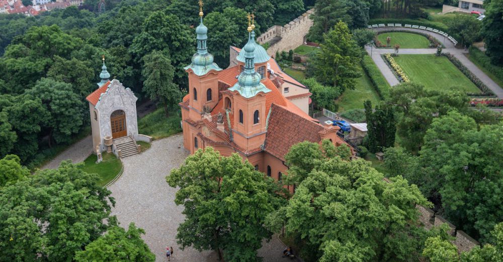 Green Roof Urban Gardens - Aerial photography of a historic European church surrounded by lush greenery and cityscape.