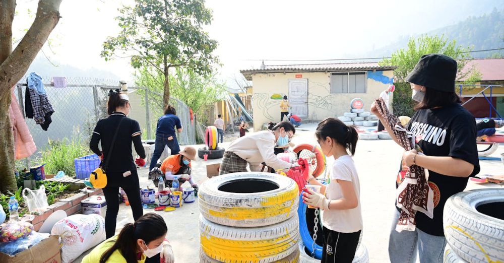 Workshop Urban Gardens - Children and adults collaborate on a colorful tire painting project in an outdoor community space.